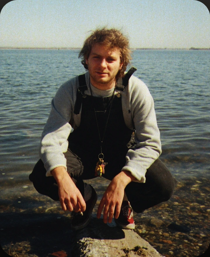 Album artwork for Another One by Mac DeMarco: a young man crouching on rocks at the edge of the sea